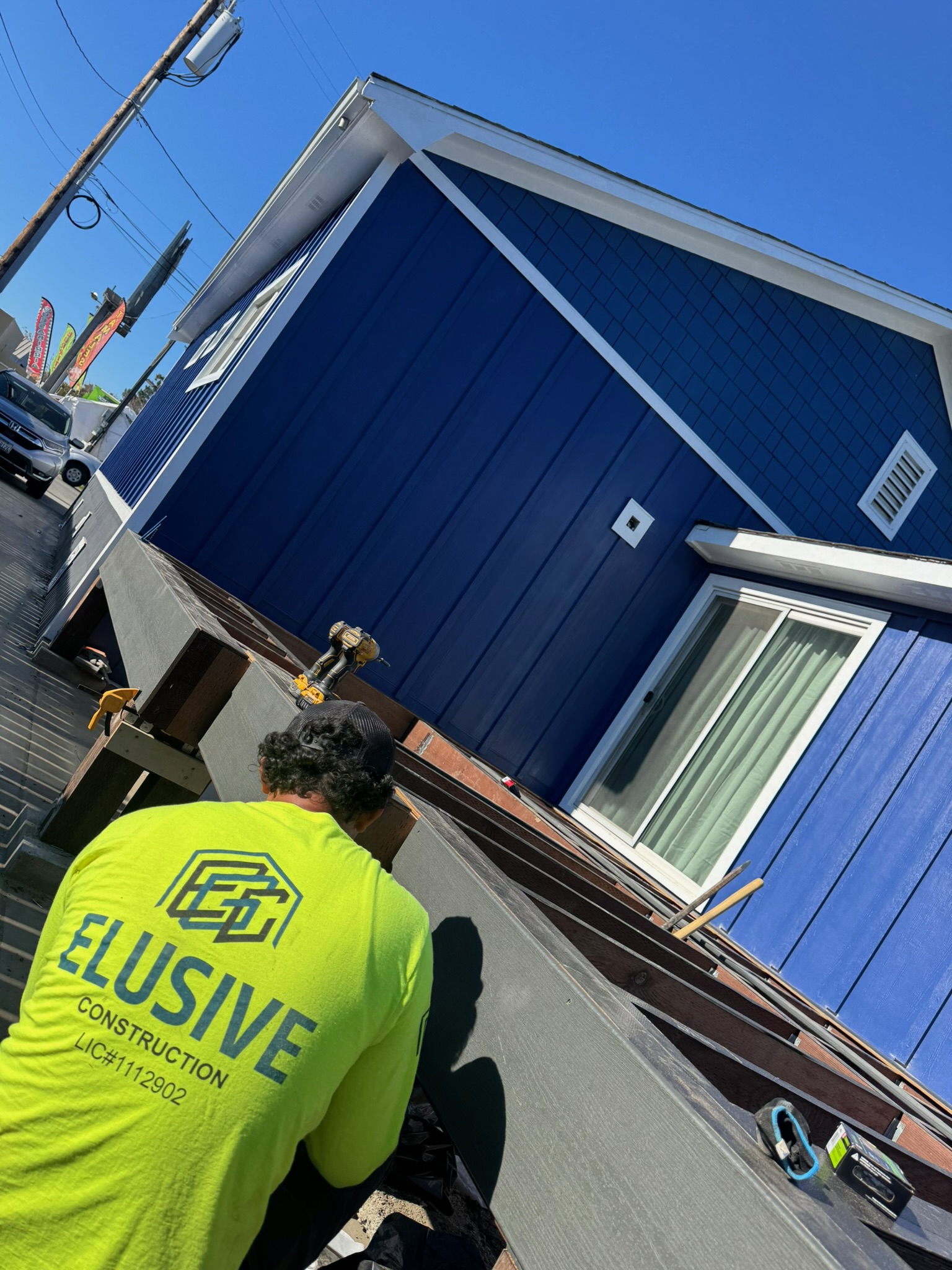 Elusive Construction crew member in a branded shirt fitting exterior siding on a San Jose home