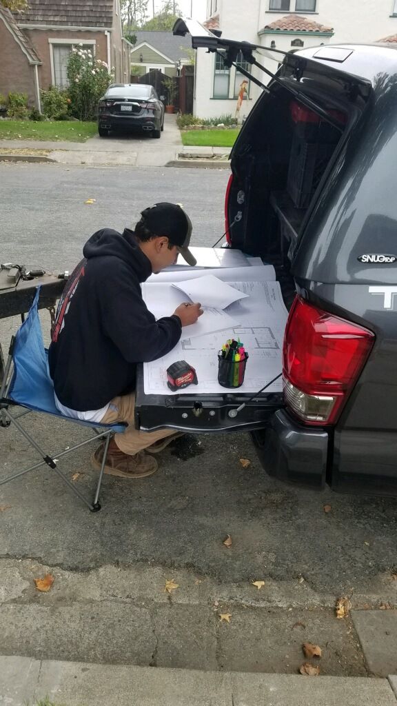 Reading a set of construction drawings spread across a pickup tailgate, with highlighters and a tape measure