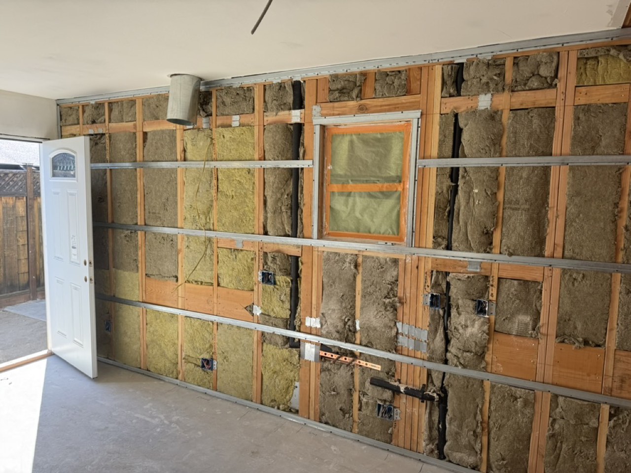 Mineral wool insulation between studs with metal furring channels installed before drywall