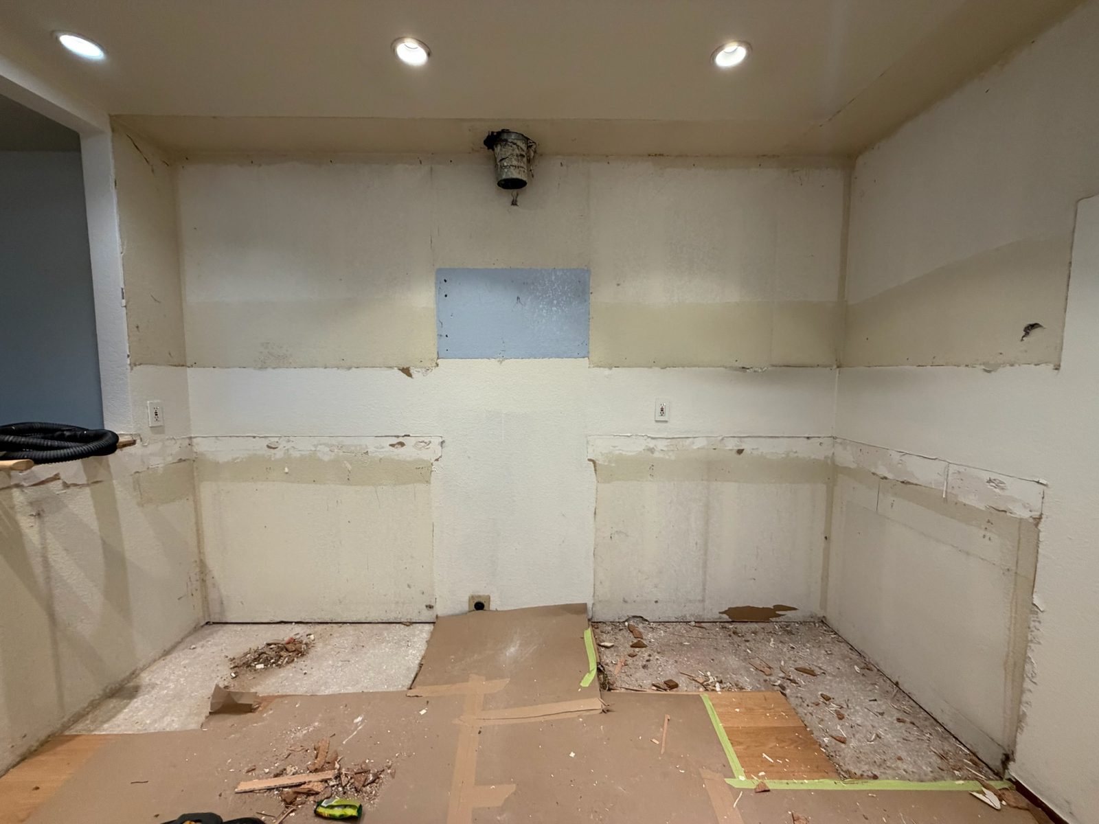 Kitchen after demolition with cabinets and counters removed, floor protected and the room swept clean